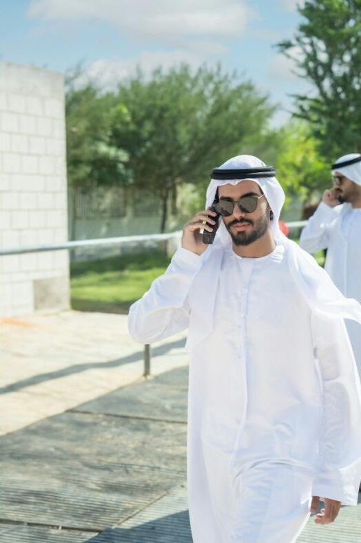 A man in a kandura taking a call outdoors